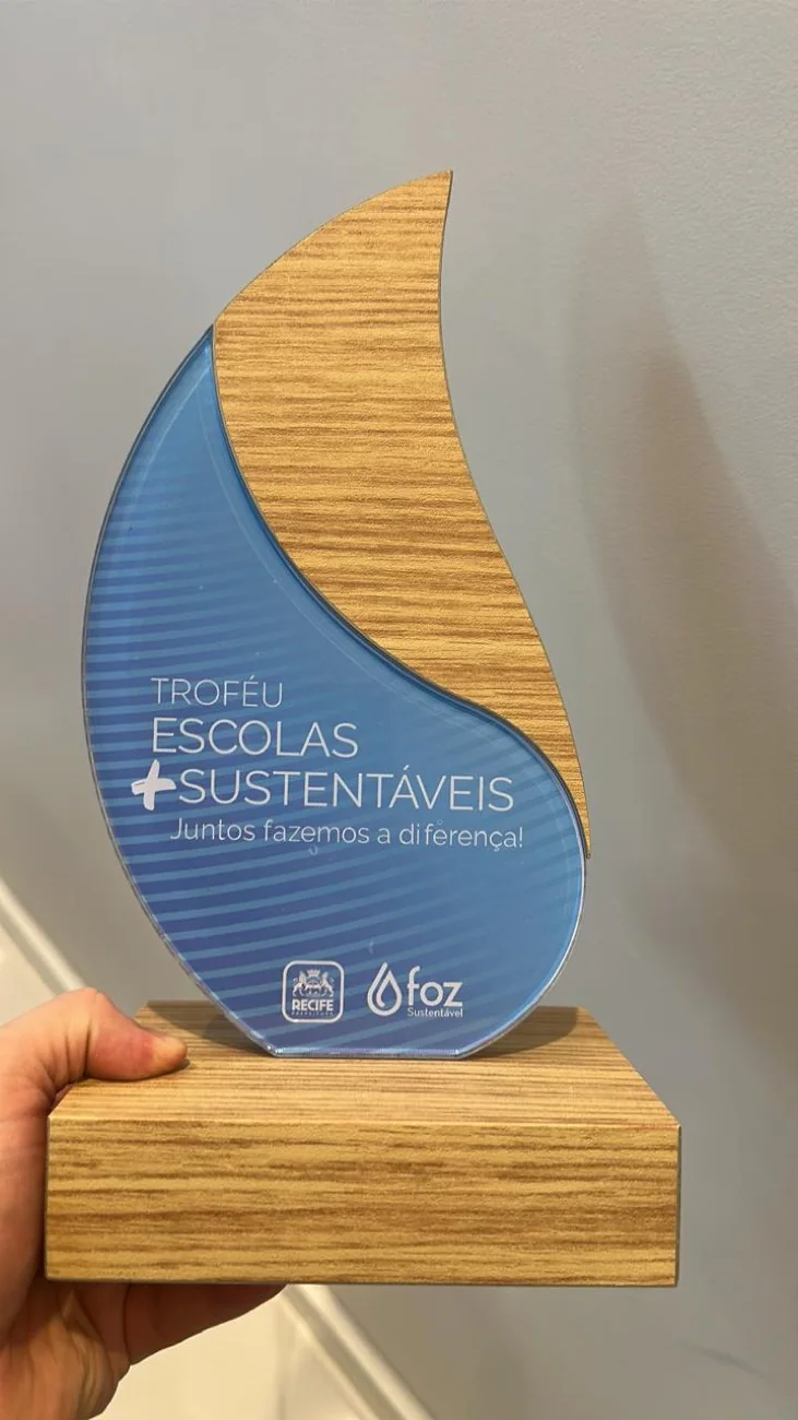 Troféu Escolas +Sustentáveis · troféu físico real em acrílico e madeira, com a marca FOZ